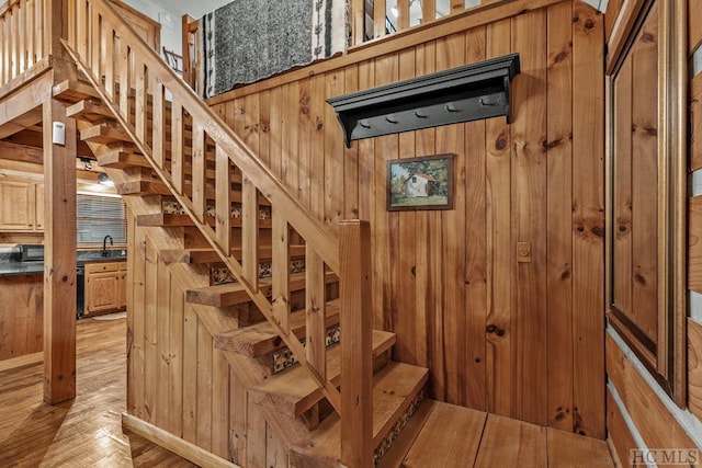 staircase with sink, hardwood / wood-style floors, and wooden walls