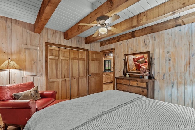 bedroom featuring wooden walls, a closet, ceiling fan, wooden ceiling, and beam ceiling