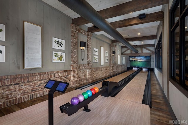 recreation room with bowling, beamed ceiling, dark hardwood / wood-style flooring, and brick wall