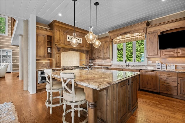 57 Loch Dr, Glenville, NC 28736 - kitchen with a center island with sink, light stone countertops, backsplash, brown cabinets, and light wood-style flooring