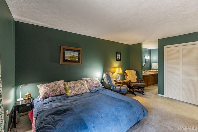 carpeted bedroom with sink, a closet, a textured ceiling, and ensuite bathroom