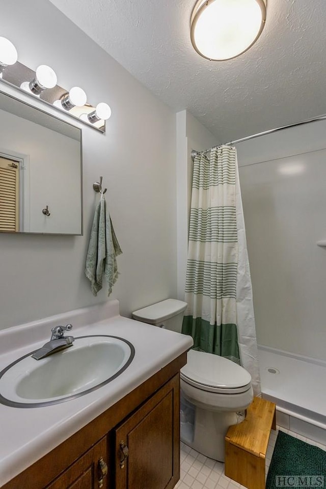 bathroom featuring walk in shower, vanity, toilet, and a textured ceiling