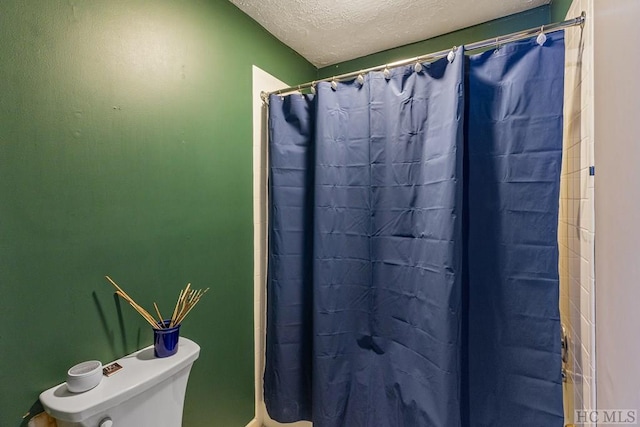 bathroom featuring toilet, curtained shower, and a textured ceiling