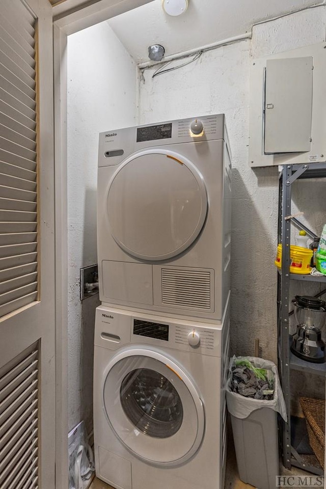 clothes washing area with stacked washer and dryer and electric panel