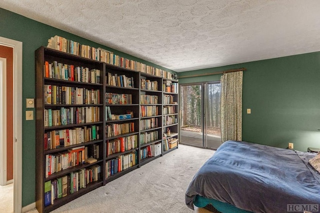 carpeted bedroom with a textured ceiling and access to outside