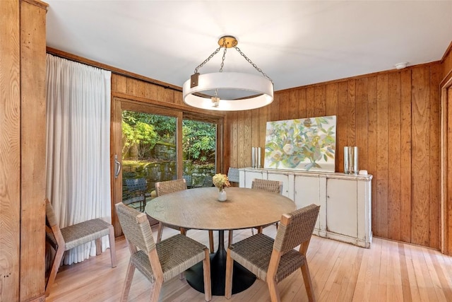 dining area with light wood-type flooring and wood walls