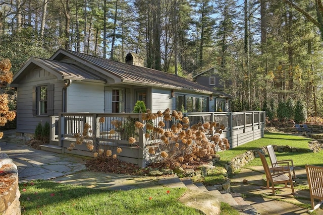 view of front of house with a chimney, a standing seam roof, metal roof, and a wooden deck