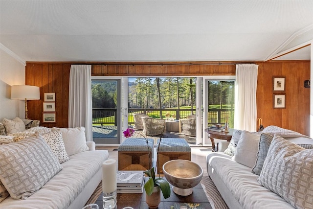 living room with ornamental molding, wood walls, and lofted ceiling