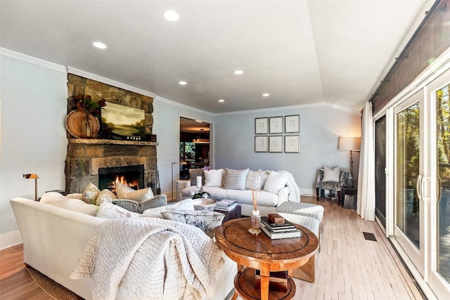living area with a stone fireplace, ornamental molding, baseboards, and light wood-type flooring