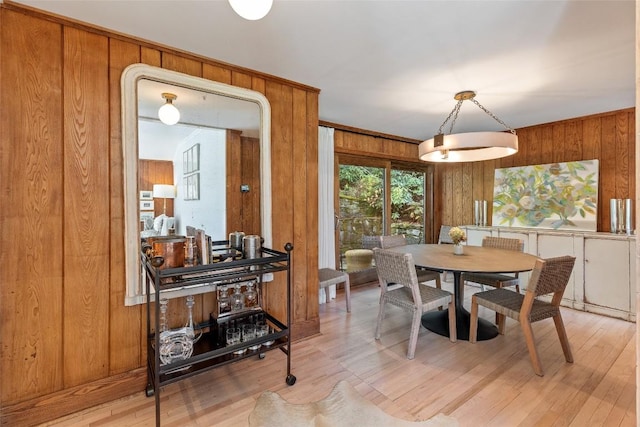 dining space with wood walls and light wood-style flooring