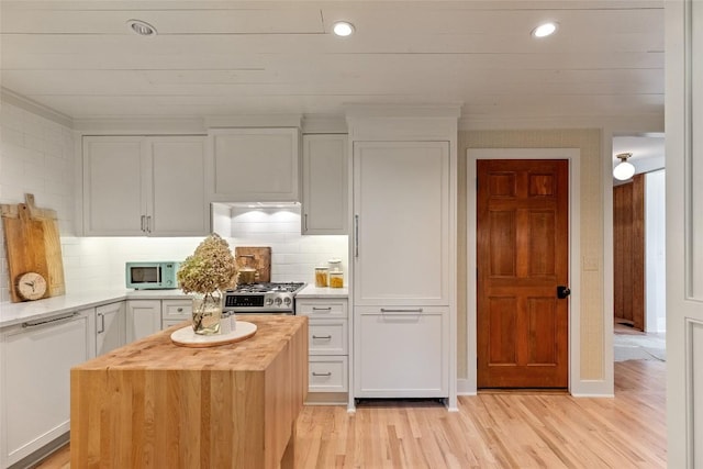 kitchen with white microwave, light wood finished floors, butcher block countertops, gas range, and backsplash
