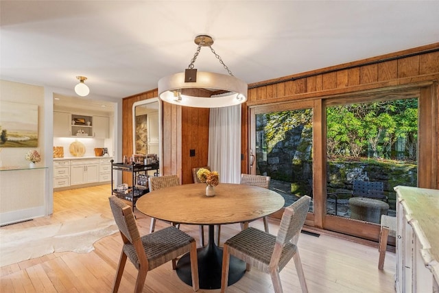 dining room featuring wood walls and light wood-style flooring