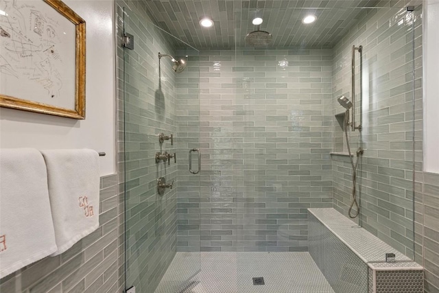 full bathroom with tile walls, a stall shower, and recessed lighting