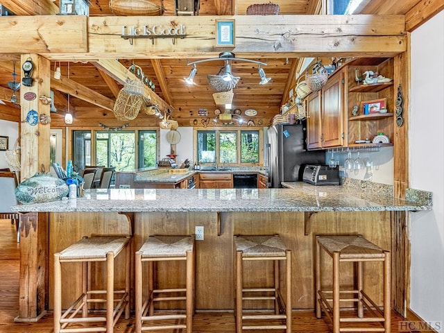 kitchen with light stone countertops, wood ceiling, kitchen peninsula, vaulted ceiling, and a breakfast bar