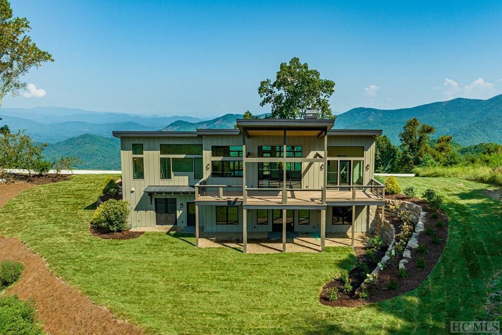 back of property with a mountain view and a lawn