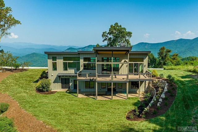 back of property with a mountain view and a lawn