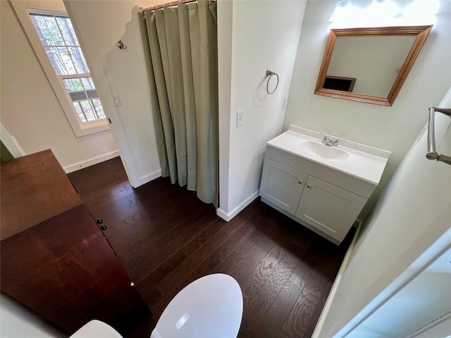 bathroom with toilet, vanity, baseboards, and wood finished floors