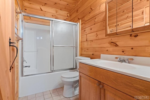 full bathroom featuring wooden walls, shower / bath combination with glass door, tile patterned flooring, vanity, and toilet