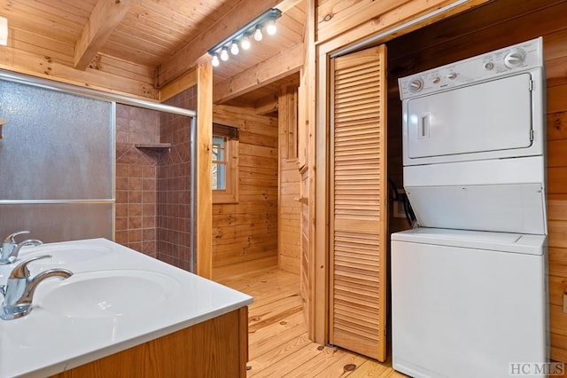 bathroom with stacked washer and dryer, wood ceiling, wooden walls, and beamed ceiling