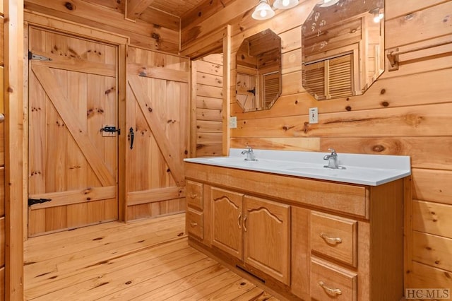 bathroom featuring hardwood / wood-style flooring, vanity, and wood walls