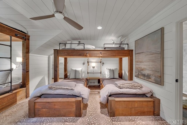 bedroom with ceiling fan and wood walls