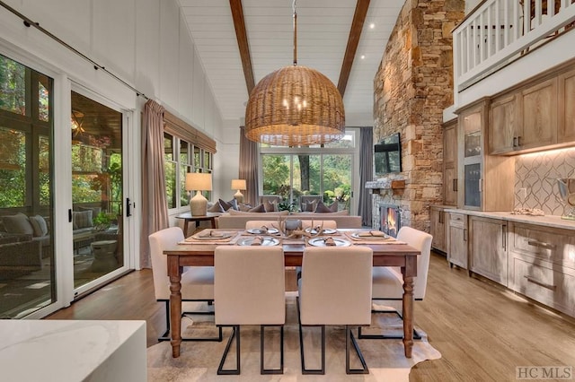 dining space featuring beamed ceiling, light hardwood / wood-style floors, and high vaulted ceiling