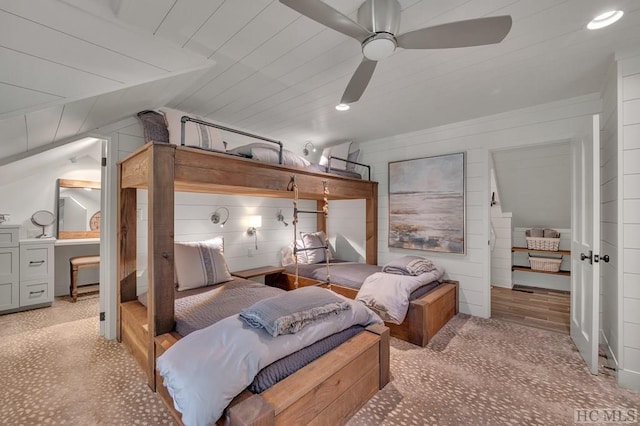 bedroom with lofted ceiling, wooden walls, and ceiling fan