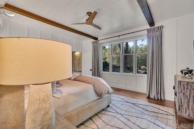 bedroom with hardwood / wood-style flooring, ceiling fan, and beamed ceiling