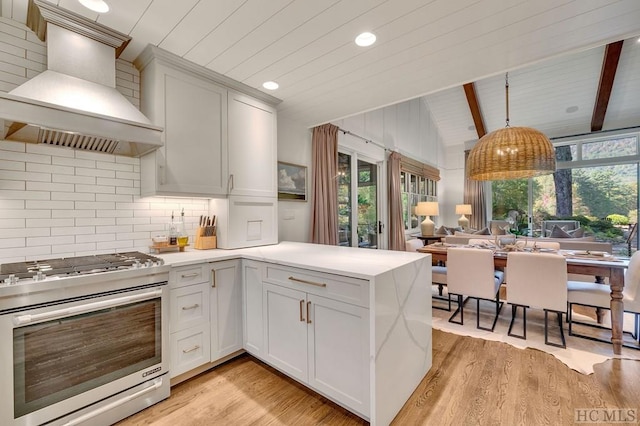 kitchen featuring high end range, white cabinetry, lofted ceiling with beams, and custom range hood