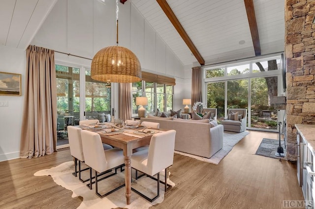 dining space with high vaulted ceiling, beam ceiling, and light hardwood / wood-style floors