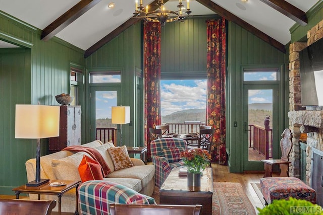 living room featuring a fireplace, light hardwood / wood-style floors, lofted ceiling with beams, and a notable chandelier