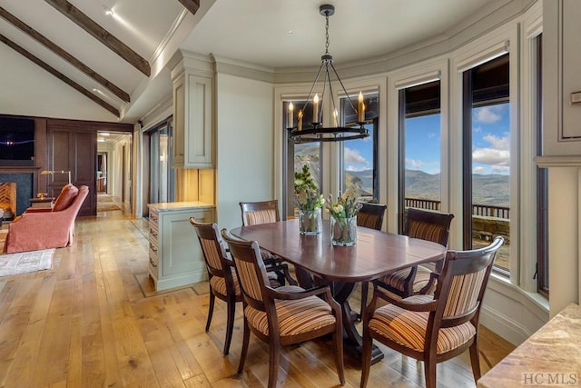 dining room with a mountain view, vaulted ceiling with beams, an inviting chandelier, and light hardwood / wood-style floors