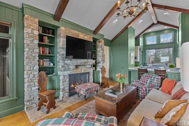 living room featuring light hardwood / wood-style flooring, beam ceiling, a stone fireplace, and built in shelves