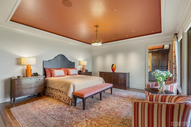 bedroom with hardwood / wood-style floors, a tray ceiling, and ornamental molding