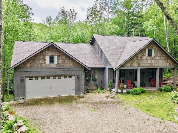 11 Feldspar Ln, Sapphire, NC 28774 - view of front of house with dirt driveway, a shingled roof, a garage, a porch, and board and batten siding