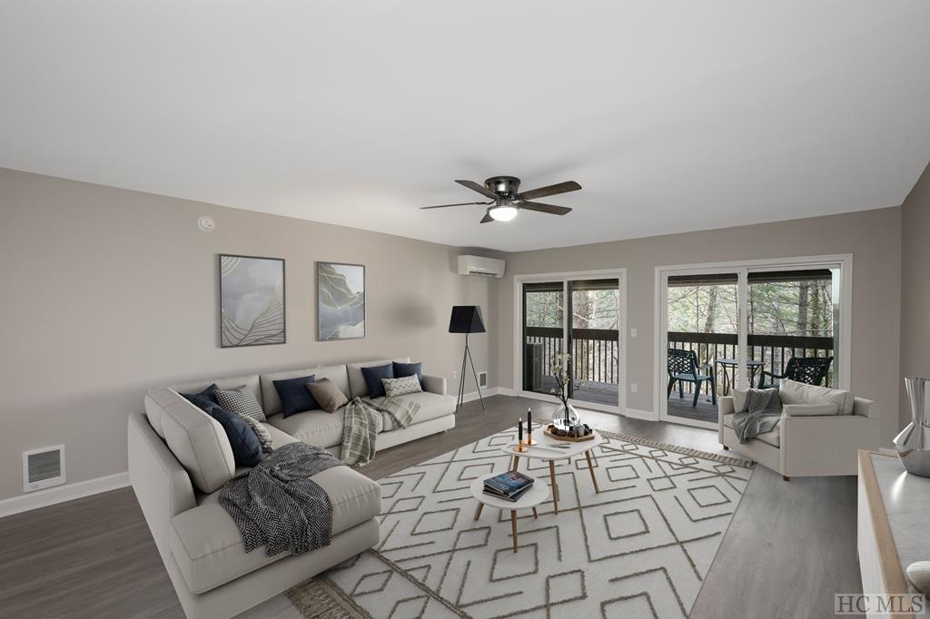 living room with hardwood / wood-style flooring, ceiling fan, and an AC wall unit