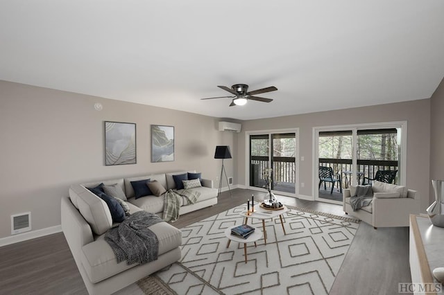 living room with hardwood / wood-style flooring, ceiling fan, and an AC wall unit