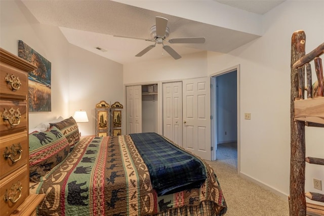 bedroom featuring carpet, two closets, a textured ceiling, and ceiling fan