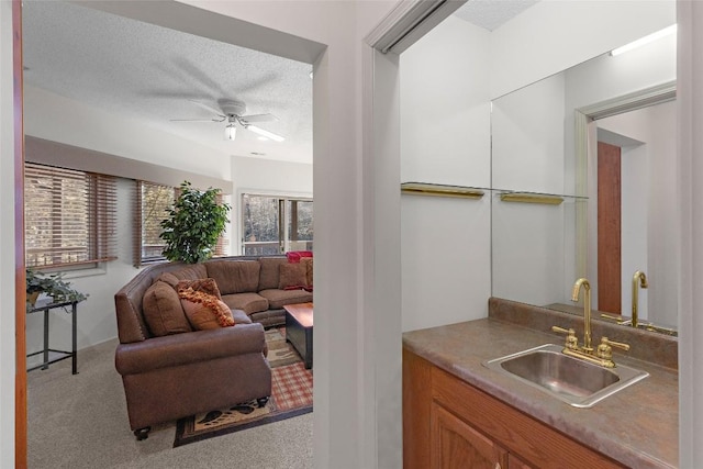 interior space with ceiling fan, sink, light colored carpet, and a textured ceiling