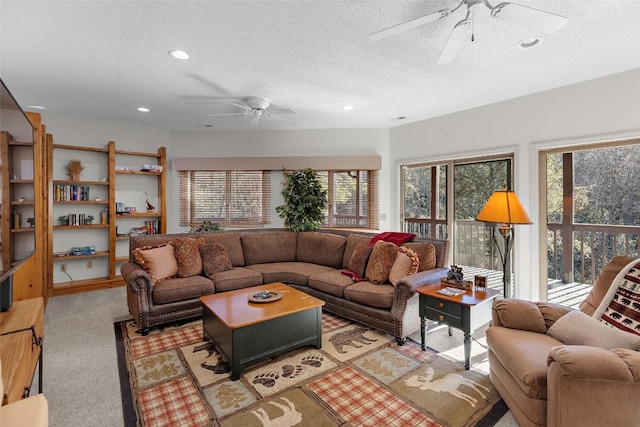 living room featuring ceiling fan, light carpet, and a textured ceiling