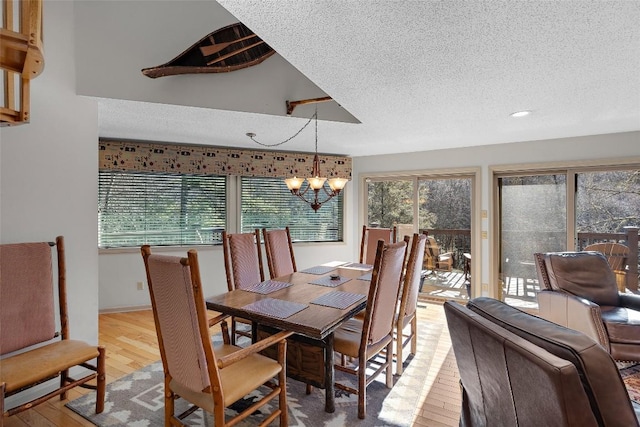 dining area featuring an inviting chandelier, a textured ceiling, and light wood-type flooring