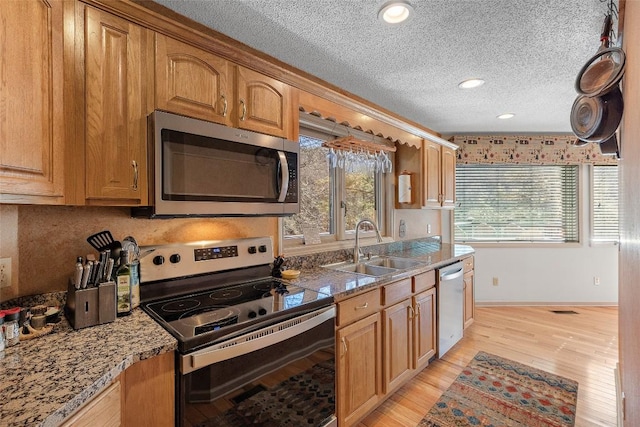 kitchen featuring stainless steel appliances, sink, a textured ceiling, and light hardwood / wood-style flooring