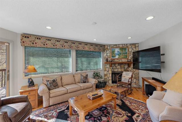 living room with wood-type flooring, a fireplace, and a textured ceiling