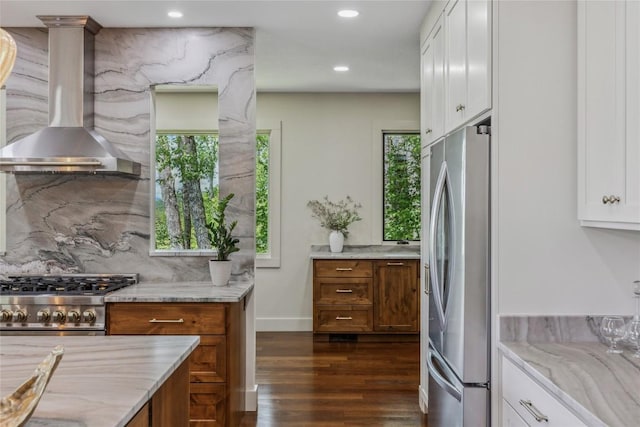 451 Country Club Dr, Highlands, NC 28741 - kitchen with wall chimney exhaust hood, appliances with stainless steel finishes, brown cabinets, light stone countertops, and dark wood-style floors