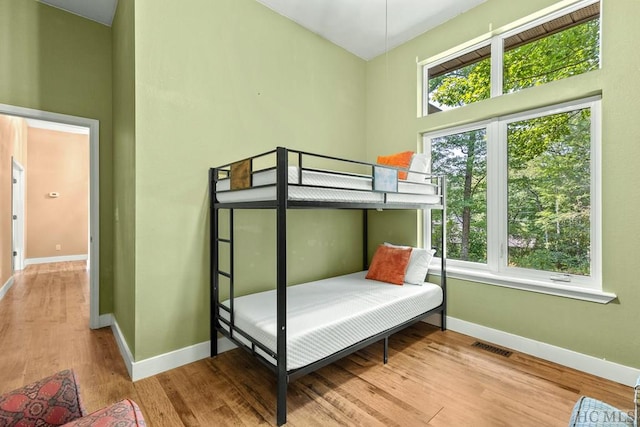 bedroom with light hardwood / wood-style floors and a high ceiling