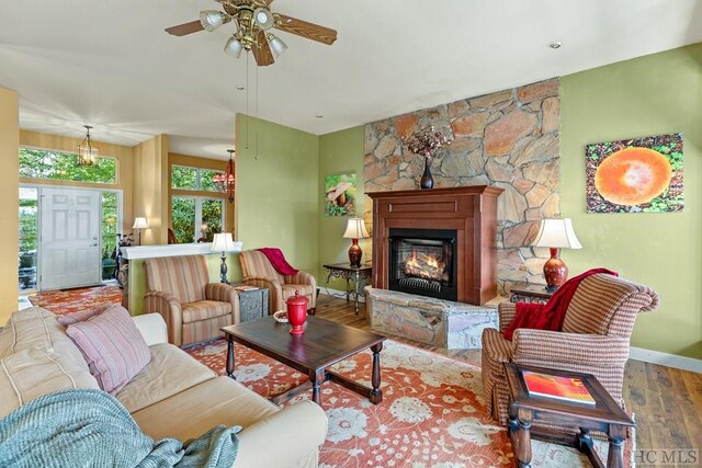 living room with a large fireplace, hardwood / wood-style floors, and ceiling fan