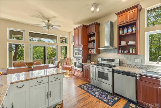 kitchen featuring appliances with stainless steel finishes, sink, wall chimney exhaust hood, and white cabinetry