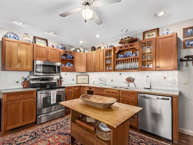 kitchen featuring stainless steel appliances, a sink, backsplash, open shelves, and brown cabinetry