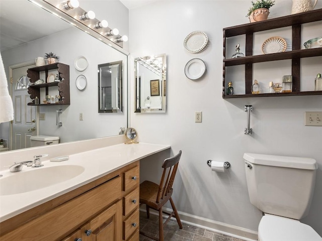 bathroom featuring toilet, vanity, and baseboards