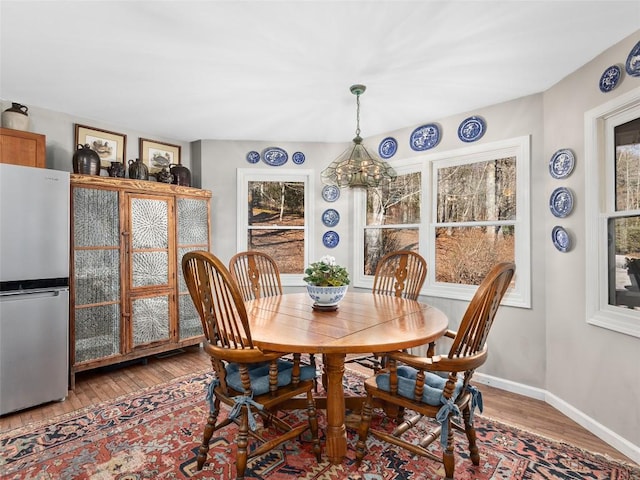 dining area featuring light wood finished floors, a chandelier, and baseboards